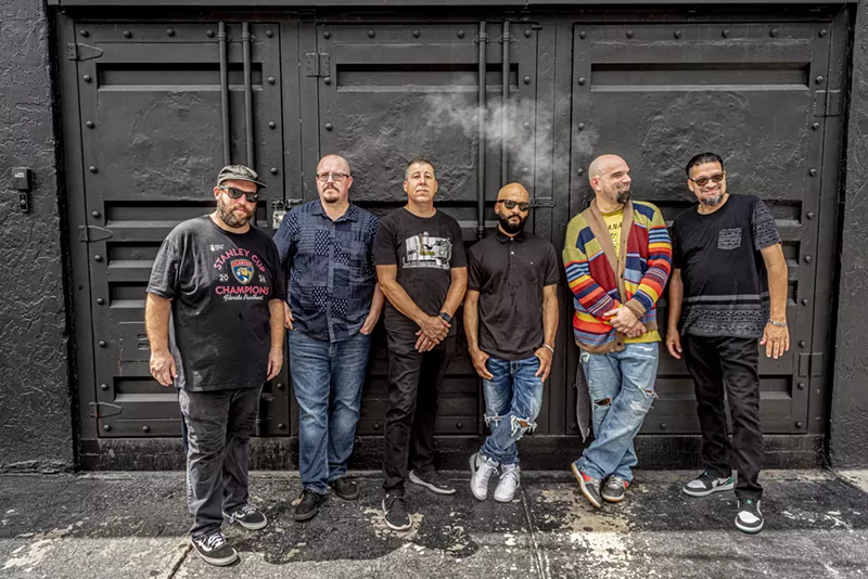 Image: Portrait of a six-piece band leaning on a wall.