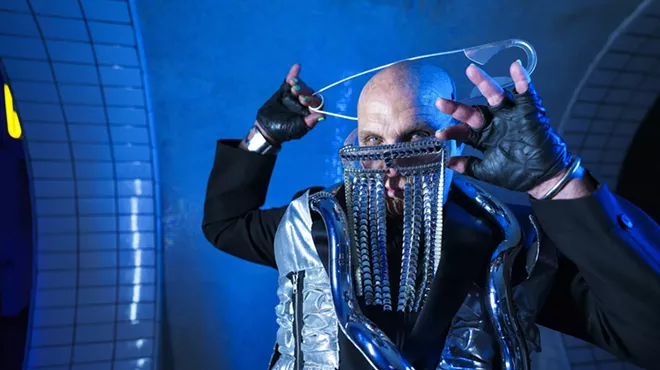 Alan T poses with a huge pin on his head and glasses with chains dropping down