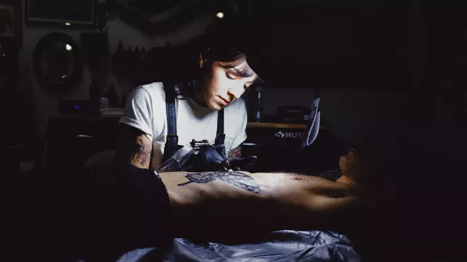 A woman tattooing a client
