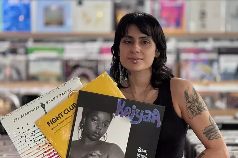 Image: A woman holding three vinyl records in her hands