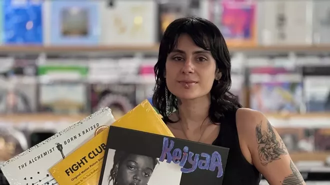 A woman holding three vinyl records in her hands