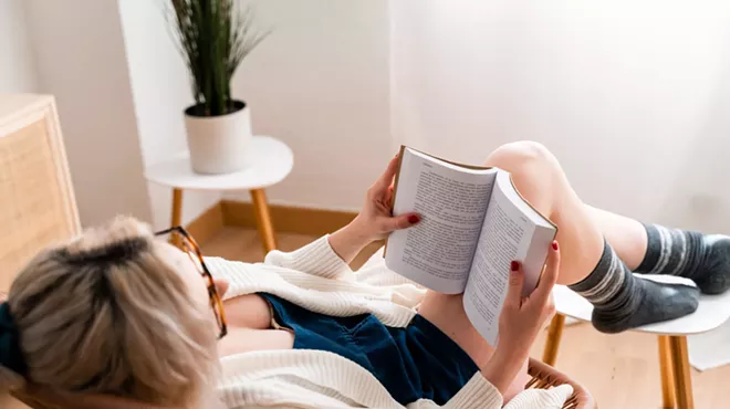 A woman sitting in a chair, reading a book