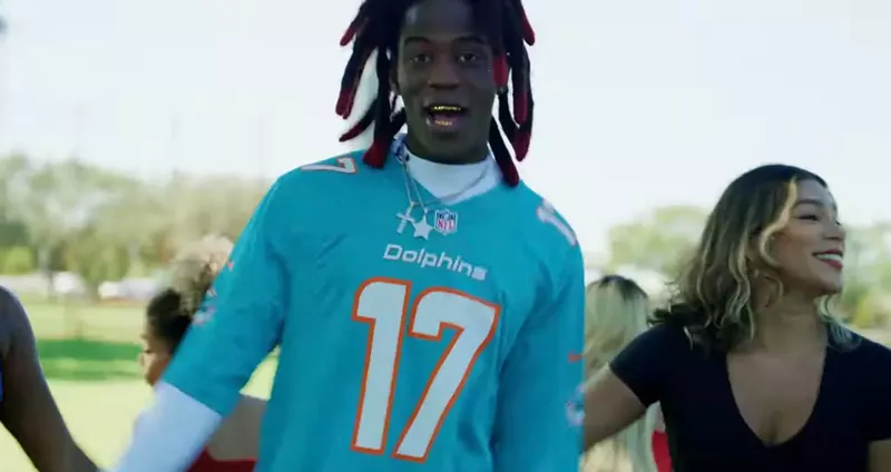 Image: A photo of Cornelius Johnson wearing a Miami Dolphins jersey during a music video.
