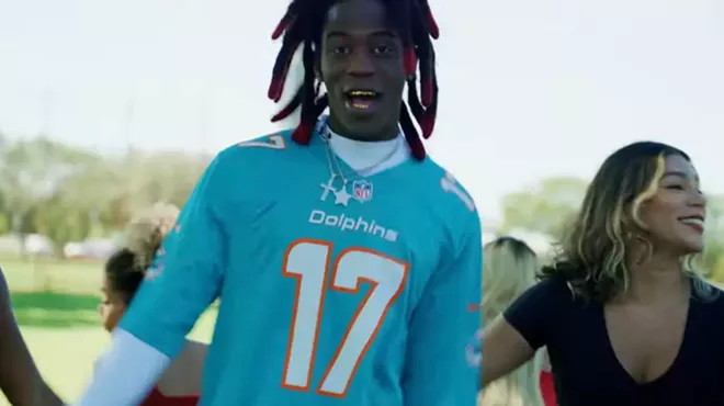A photo of Cornelius Johnson wearing a Miami Dolphins jersey during a music video.