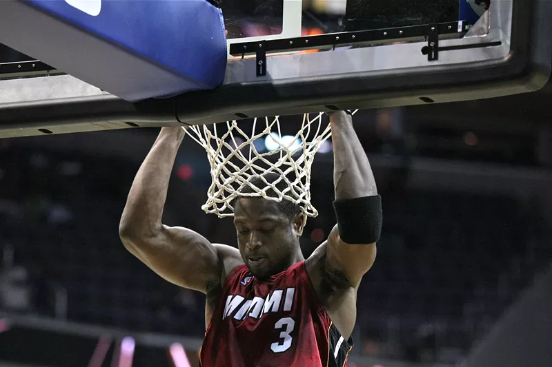 Image: 2009 photo of Dwyane Wade of the Miami Heat hanging off a basketball rim