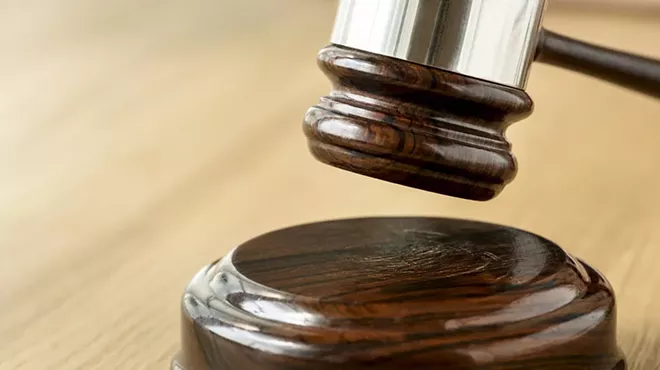 A judge's gavel hangs above a wooden surface.