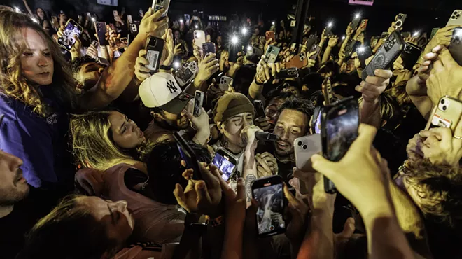fans holding phones swarm a rapper