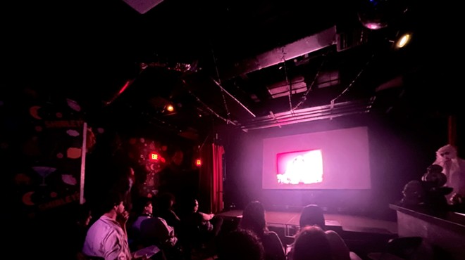 A group of people sitting in a dark room watching a film projection