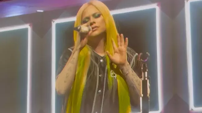 Avril Lavigne sings into a microphone onstage