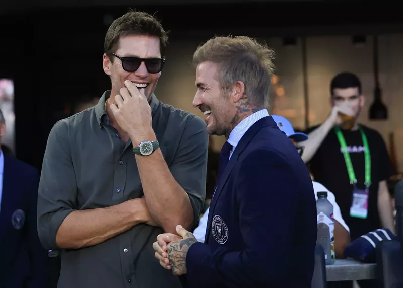 Image: two superstars sharing a moment on the sidelines at a professional soccer game