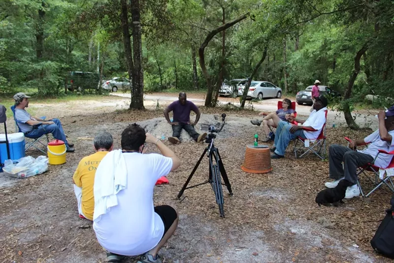 Image: A group of volunteers meet with Marvin Dunn at his property in Rosewood, Florida, where he planned to build a "peace house" 100 years after a racially motivated massacre in the town.