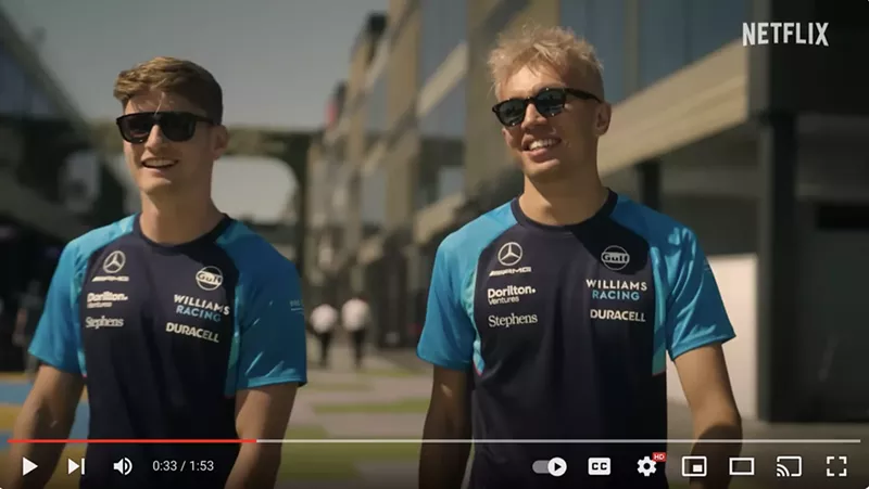 Image: Williams Racing Formula 1 drivers Logan Sargeant (left) and Alex Albon (right) walk alongside each other wearing sunglasses.