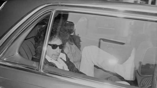 Black and white image of Bob Dylan in the back of car
