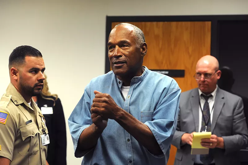 Image: O.J. Simpson clasps his hands together in a courtroom while wearing an inmate's uniform