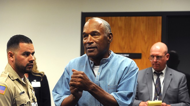 O.J. Simpson clasps his hands together in a courtroom while wearing an inmate's uniform