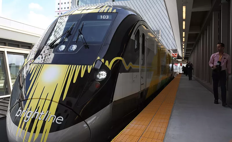 Image: A yellow and black Brightline train sits at the Miami Central terminal.