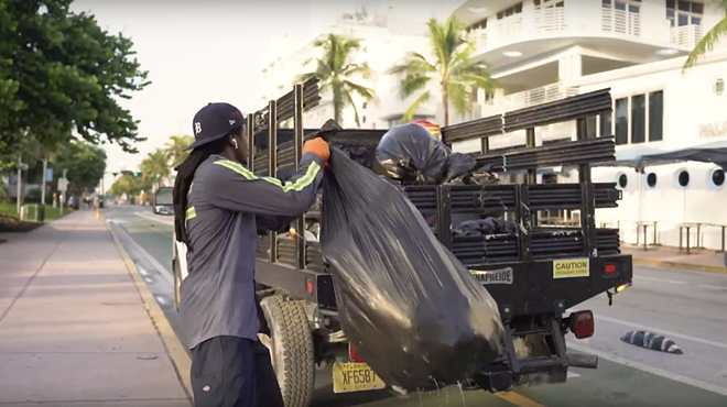 A South Florida garbage collection worker tosses trash into a truck's flatbed