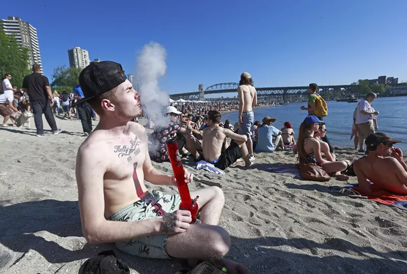 Image: A man takes a bongload of smoke as hundreds gather to celebrate 4/20 at Sunset Beach in Vancouver, Canada, in 2016.
