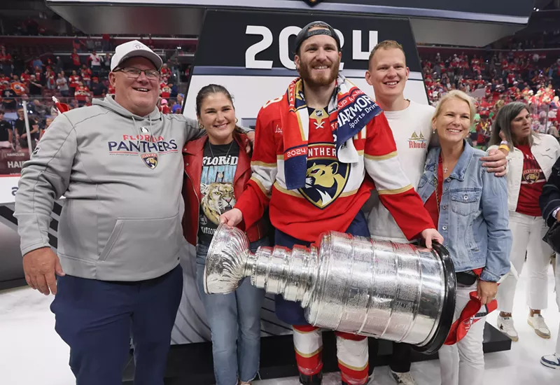 Image: Panthers player Matthew Tkachuk holds the Stanley Cup trophy as his family stands shoulder to shoulder next to him, smiling