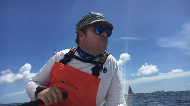 Portrait of man at sea with a sailboat in the background