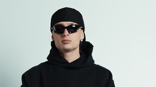 Peso Pluma wearing sunglasses and a black Balenciaga hoodie