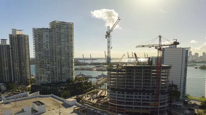Panoramic view of a skyline with a building site and cranes in the forefront
