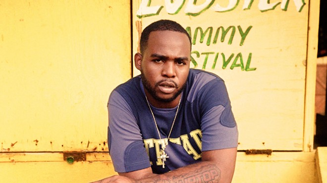 Dancehall singer Teejay with his arms cross against a yellow background