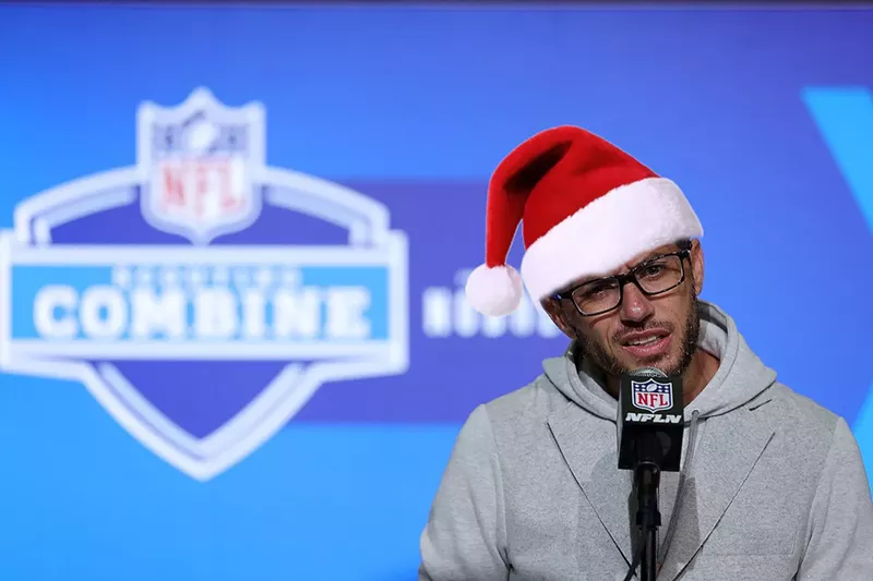 Image: photo of Miami Dolphins head coach Mike McDaniel wearing a quizzical expression at an NFL combine press conference — with a Santa hat photoshopped onto his noggin