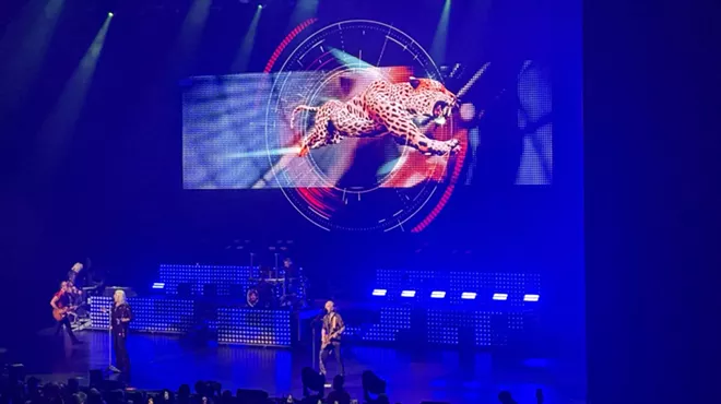 A picture of the band Def Leppard performing at the Hard Rock Live in front of a projection of a leppard.