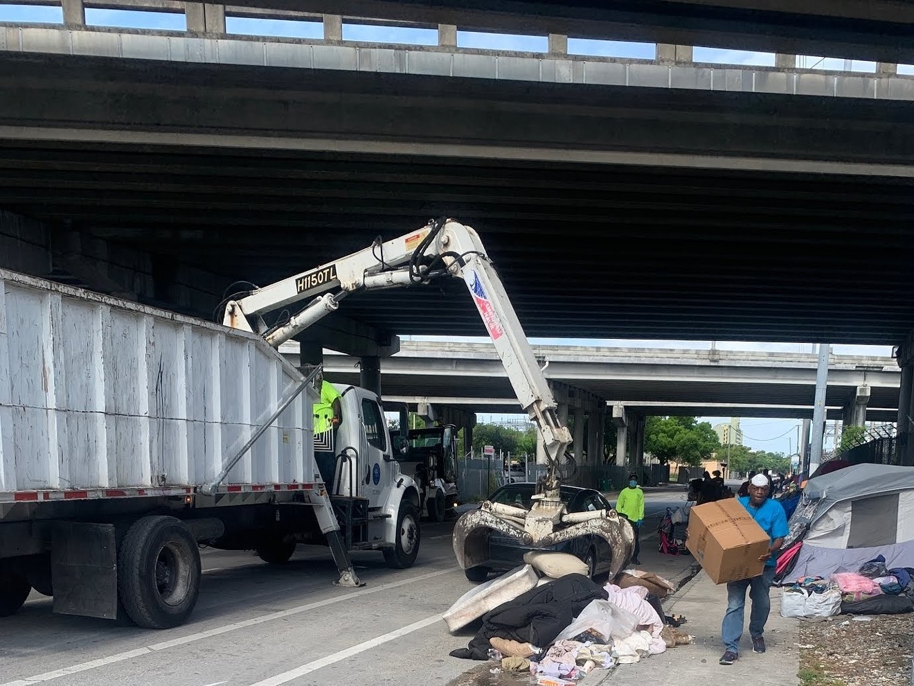Workers clear out belongings at a homeless encampment in Overtown on the morning of May 13, 2020
