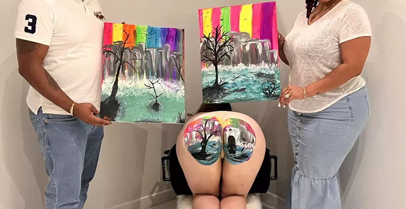 Image: two people hold canvases depicting landscapes on either side of a model's butt depicting a similar landscape