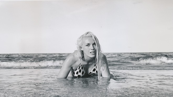 Bunny Yeager crawling out of the ocean onto the shore