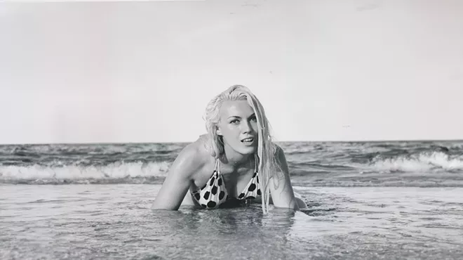 Bunny Yeager crawling out of the ocean onto the shore