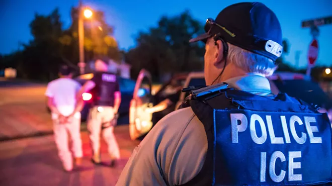 An ICE Enforcement and Removal Operations (ERO) officer arrests someone as another officer looks on