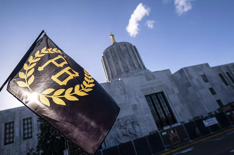 Image: A flag for the extremist Proud Boys group flies against a blue, clear sky