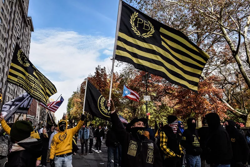 Image: A Proud Boys rally with signature yellow-and-black flags waving