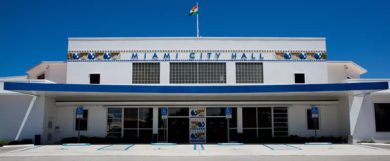 Image: Depicted is Miami City Hall, a white and blue building, on a sunny day.