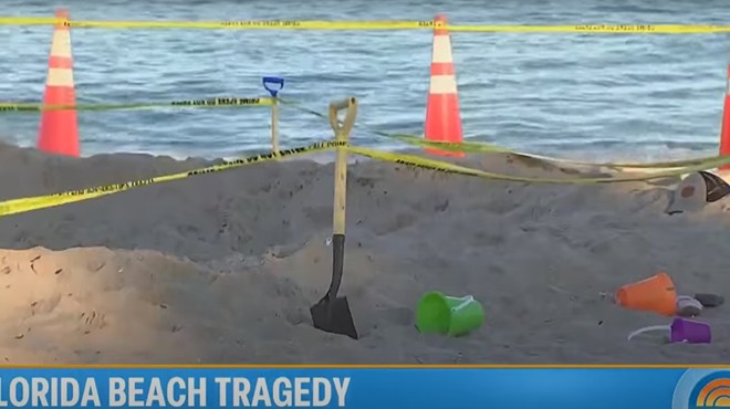 Beach toys, a shovel, and a cone sit on the beach at the site of a fatal sand collapse
