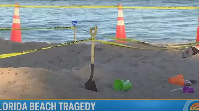 Beach toys, a shovel, and a cone sit on the beach at the site of a fatal sand collapse