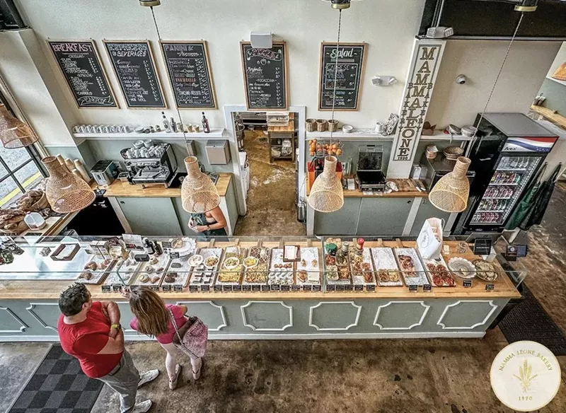 Image: a bakery with pastel hues and pastries behind glass enclosures