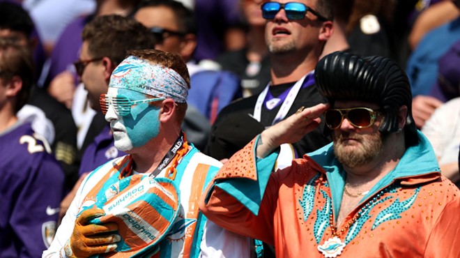 A Miami Dolphins fan in an Elvis Presley costumer salutes