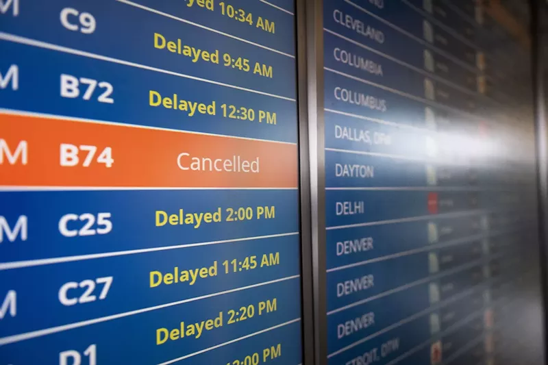 Image: close-up photo of a board showing delays and cancellations at an airport
