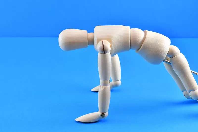 Image: stock photo of an articulated wooden figure in a kneeling position as if vomiting