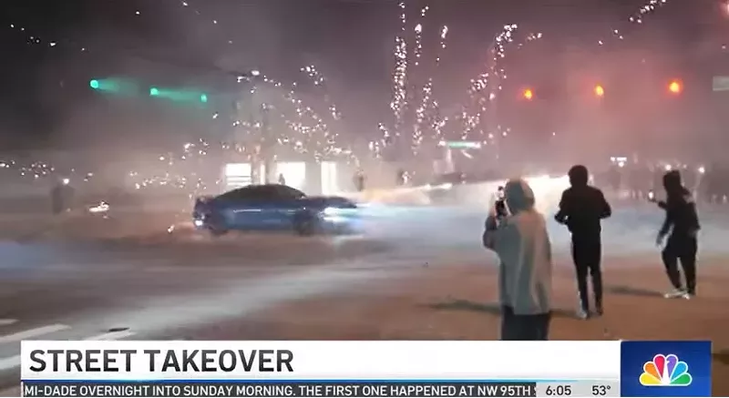 Image: A car spins around an intersection during a street takeover as fireworks explode in the background