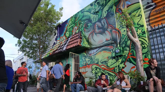 people sit and socialize outside a muralled building