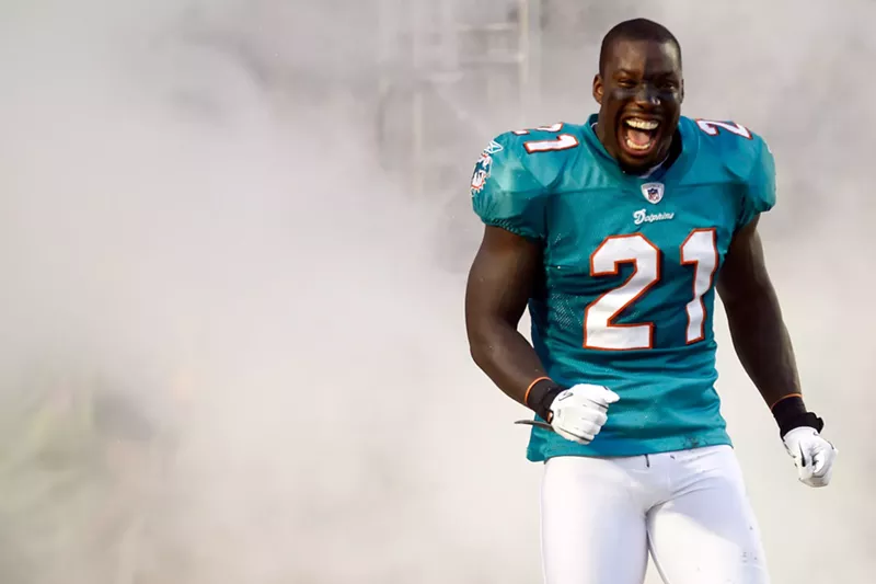 Image: color photo of Miami Dolphins cornerback Vontae Davis grinning from ear to ear as he trots onto the field surrounded by "smoke" during player introductions on September 12, 2011