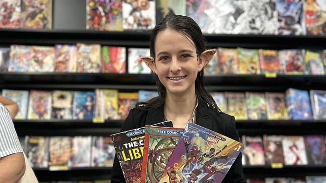 A woman with prosthetic ears holding comic books in her hands