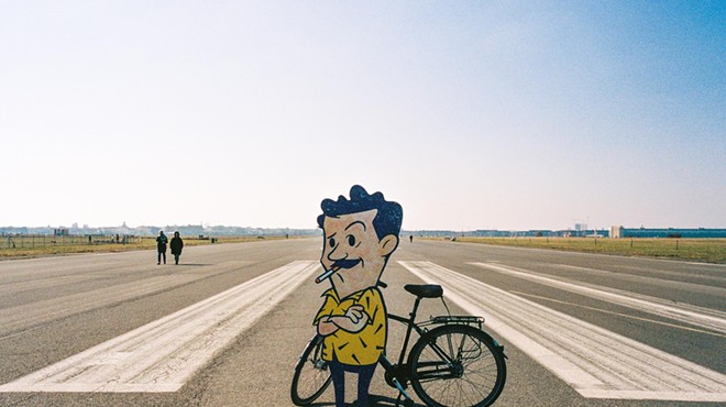 Gene On Earth's animated character in front of a bike while standing on a runway.