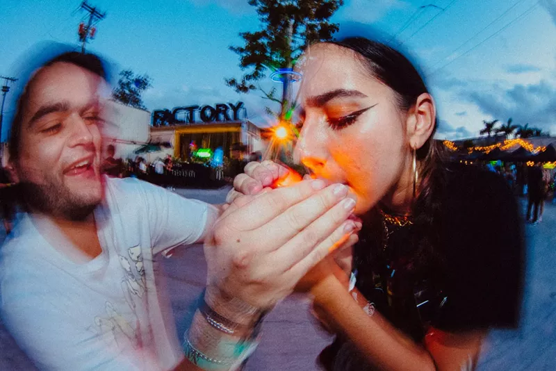Image: A man helping a woman light up a joint