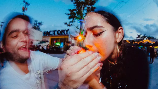 A man helping a woman light up a joint
